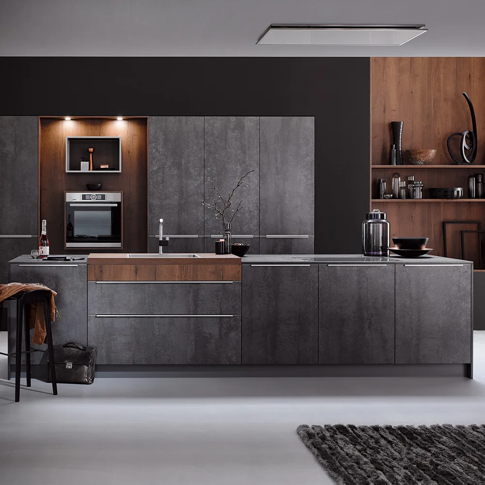 Cocina alemana premium en tonos oscuros con isla central y vitrinas iluminadas expuesta en el showroom Per Sé Küchen Madrid Retiro