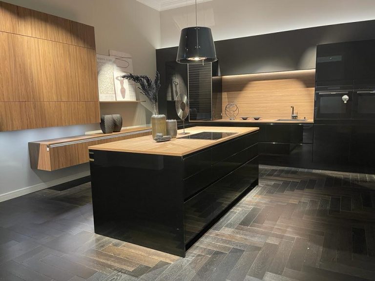 Vista frontal de cocina alemana nueva colección en negro brillante con isla en madera y encimera de madera natural, Per Sé Küchen