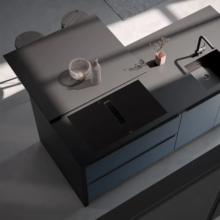 Vista cenital de isla de cocina en negro con encimera extraíble tipo mesa, placa de inducción y fregadero integrados